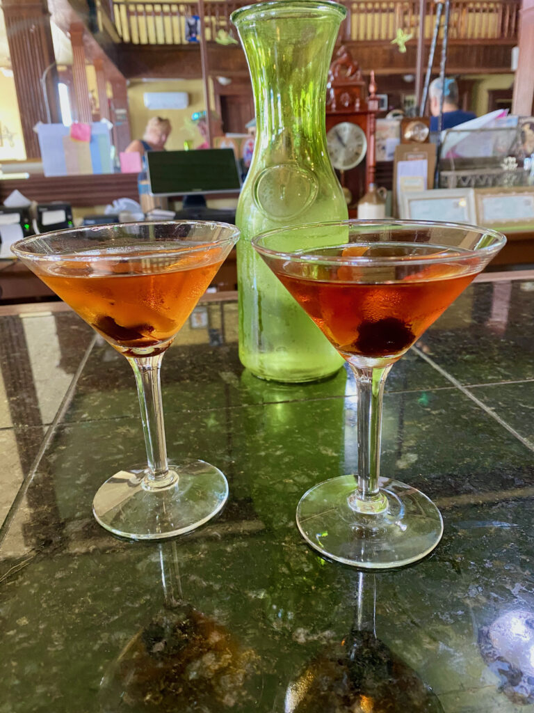 two old fashioned drinks from Flanigan's Distillery sitting on the bar with an opaque, green milk jug behind it